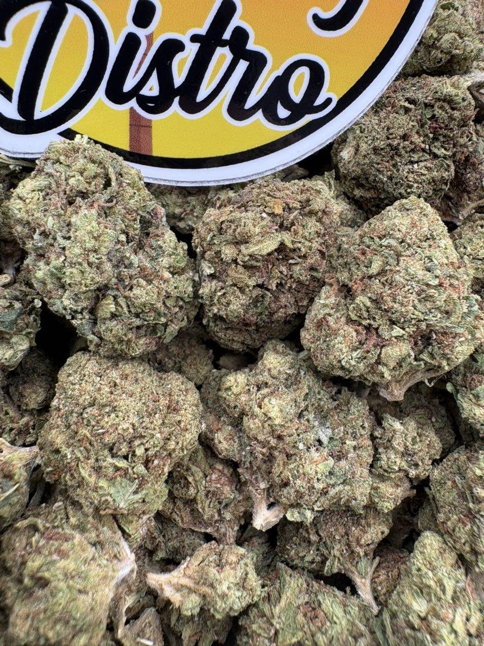 Green Cookie Monster Lows cannabis flower buds with orange pistils beside the LA Kings Distro logo Green Cookie Monster Lows cannabis flower buds with orange pistils beside the LA Kings Distro logo