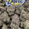 Frosty olive green and purple Gorilla Butter Lows cannabis buds beside the LA Kings Distro logo